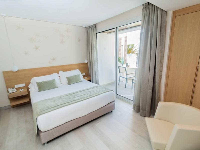 Jasny pokój hotelowy z łóżkiem podwójnym, balkonem i nowoczesnym wyposażeniem.