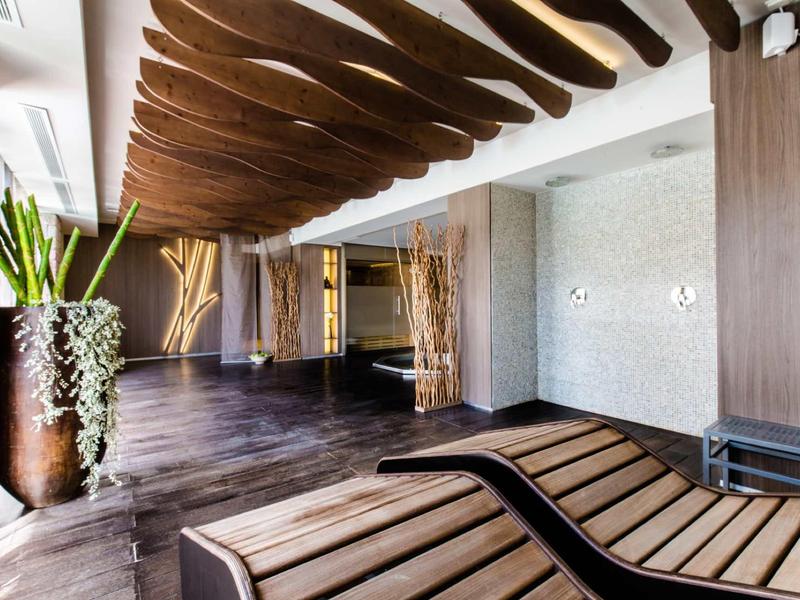 Nowoczesne lobby hotelowe z drewnianymi panelami, dekoracyjnymi wazami i drewnianymi fotelami.