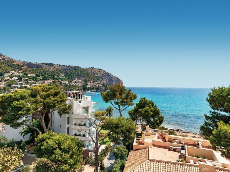 Vue sur la mer Méditerranée et des maisons avec des arbres le long de la côte sous un ciel dégagé.