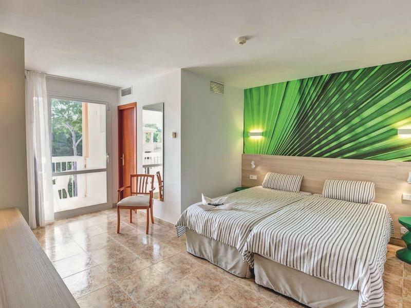 Chambre d'hôtel moderne avec deux lits simples et une fresque murale de feuille verte.