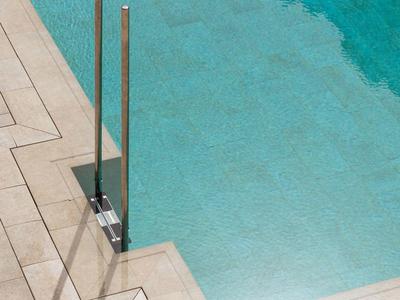 Pianerottolo con corrimano in acciaio inox e acqua turchese in una piscina dell'hotel.
