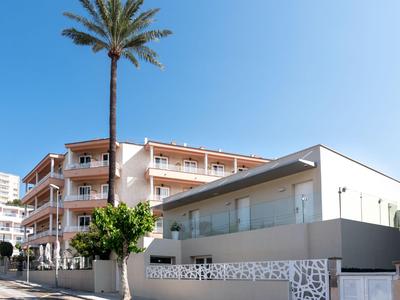 Complesso alberghiero moderno con balconi, palme e cielo azzurro limpido sullo sfondo.