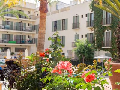 Cortile con piante fiorite e palme davanti a moderni edifici alberghieri.