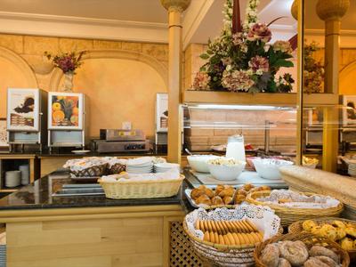 Buffet con pasticcini freschi e piatti freddi in una sala da pranzo d'hotel illuminata caldamente.