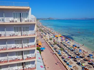 Uitzicht op een hotel met balkons en een druk strand met parasols en helder zeewater.