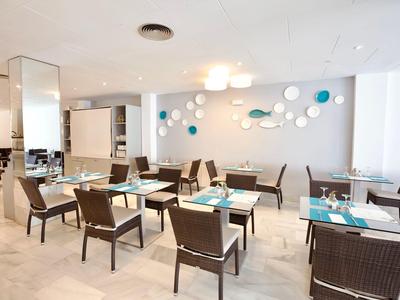 Modern restaurant met heldere muren, eenvoudige meubels en decoratieve ronde wandobjecten.