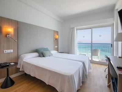 Hotelkamer met twee eenpersoonsbedden, groot raam met uitzicht op zee en modern interieur.