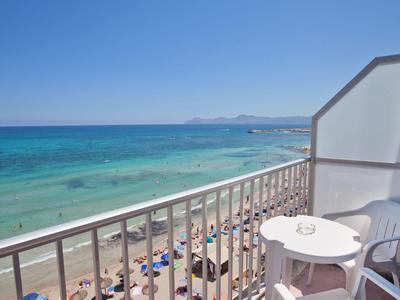 Balkon met witte tafel en stoelen met uitzicht op het strand en de blauwe zee.