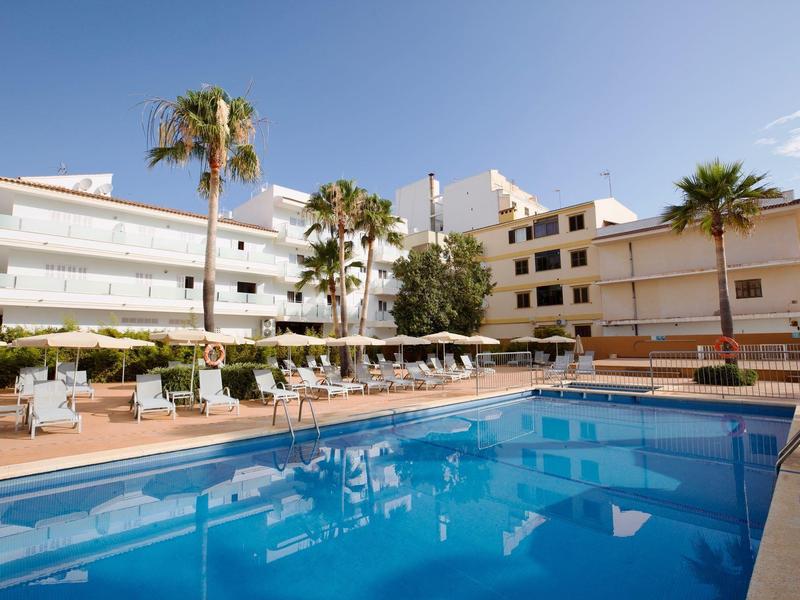 Complesso alberghiero moderno con piscina all'aperto e lettini sotto un cielo azzurro.