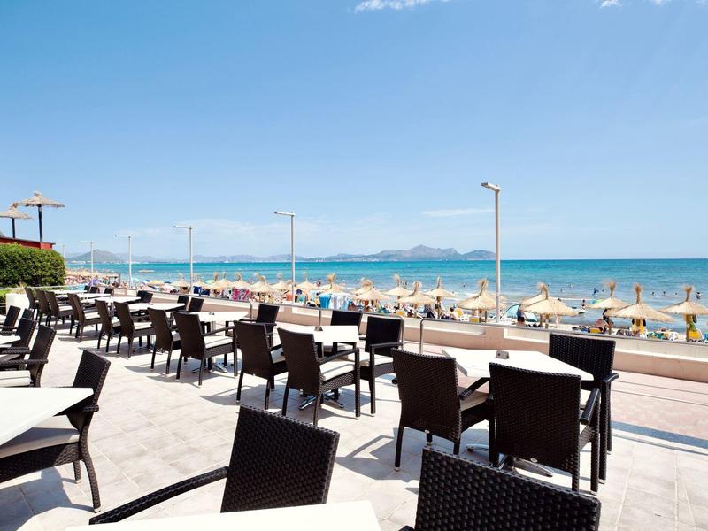 Terrazza di un ristorante con vista sulla spiaggia e sul mare in una giornata di sole.