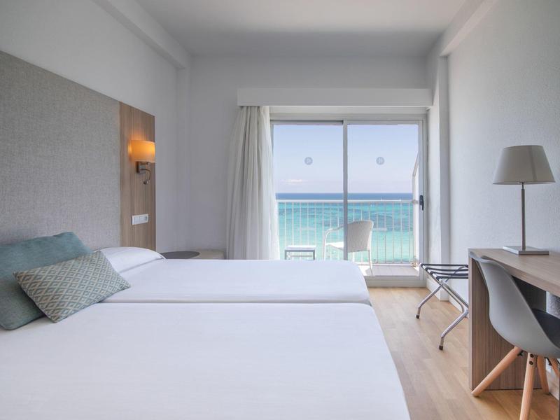 Camera d'hotel moderna con due letti, vista mare e scrivania