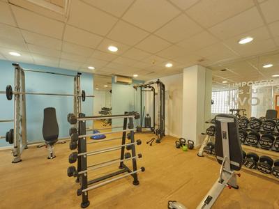 Innenansicht eines modernen Fitnessraums in einem Hotel mit Geräten und Gewichten.