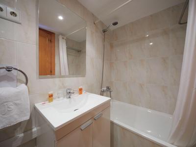 Kompaktes Badezimmer mit weißem Waschbecken, Badewanne und Handtuchhalter an der Wand.
