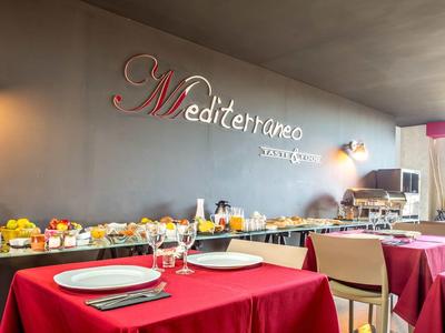 Restauracja z czerwonymi obrusami na stołach i bufetem z owocami i napojami przy ścianie