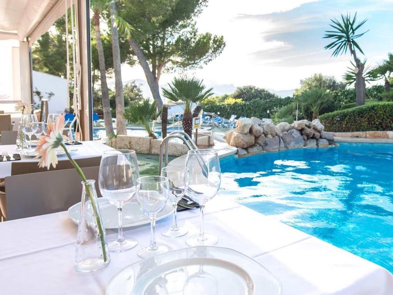 Elegancka restauracja przy basenie z nakrytymi stołami i odprężającą atmosferą na świeżym powietrzu.