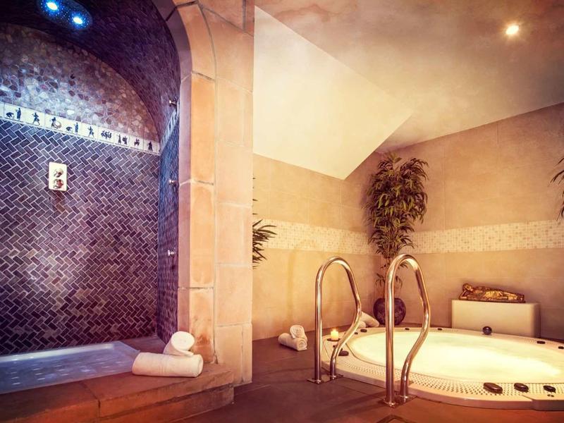 Luksusowa strefa spa z jacuzzi, mozaikową ścianą i nastrojowym oświetleniem