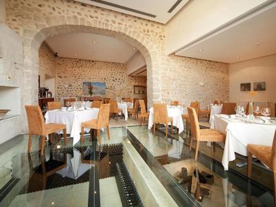 Interior of an elegant restaurant with glass floor and stone walls.