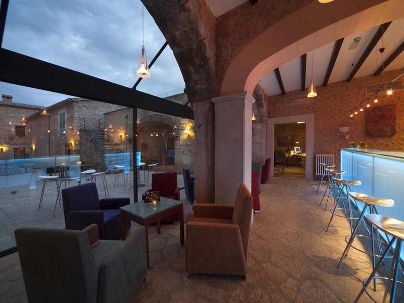Cozy hotel bar with seating and a view of the pool at dusk.