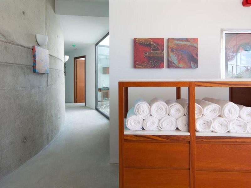 Modern hotel interior with rolled white towels on wooden shelves and concrete wall.