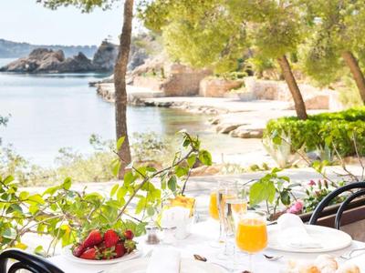 Stół z śniadaniem i sokiem pomarańczowym na tarasie z widokiem na wybrzeże i morze.