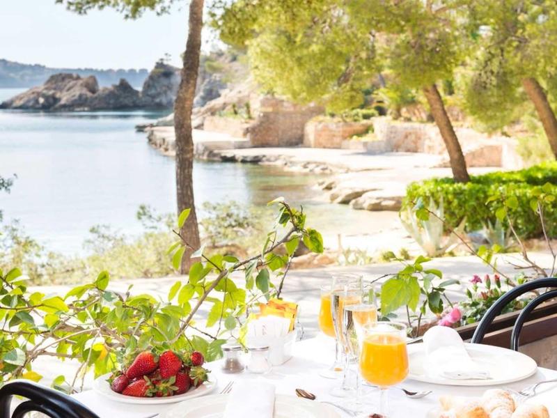 Stół z śniadaniem i sokiem pomarańczowym na tarasie z widokiem na wybrzeże i morze.