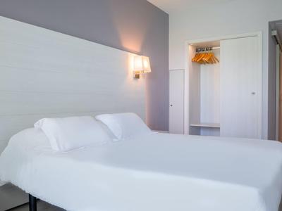 Nowoczesny pokój hotelowy z dwoma pojedynczymi łóżkami i otwartą szafą.