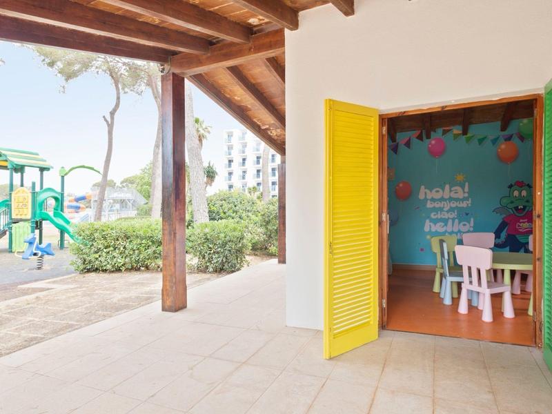 Barevná herna pro děti s otevřeným vstupem a venkovním hřištěm pod dřevěnou střechou.