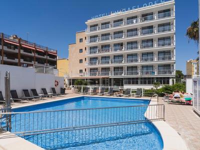 Moderner Hotelpool mit blauen Liegestühlen und sechsstöckigem Gebäude im Hintergrund bei klarem Himmel.