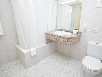 Bright bathroom with shower curtain, sink, mirror, and toilet.