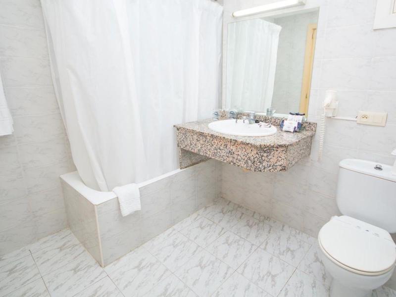 Bright bathroom with shower curtain, sink, mirror, and toilet.