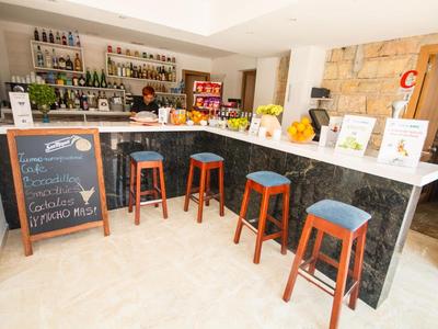 Moderner Hotelbarbereich mit schwarzen Tresen, Holzstühlen und Getränken im Hintergrund.