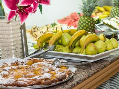 Frisches Obst und Gebäck auf einem Buffet im Restaurant mit Blumendekor.