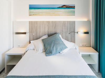 Modern bedroom with white bed, two nightstands, and a sea picture above the headboard.