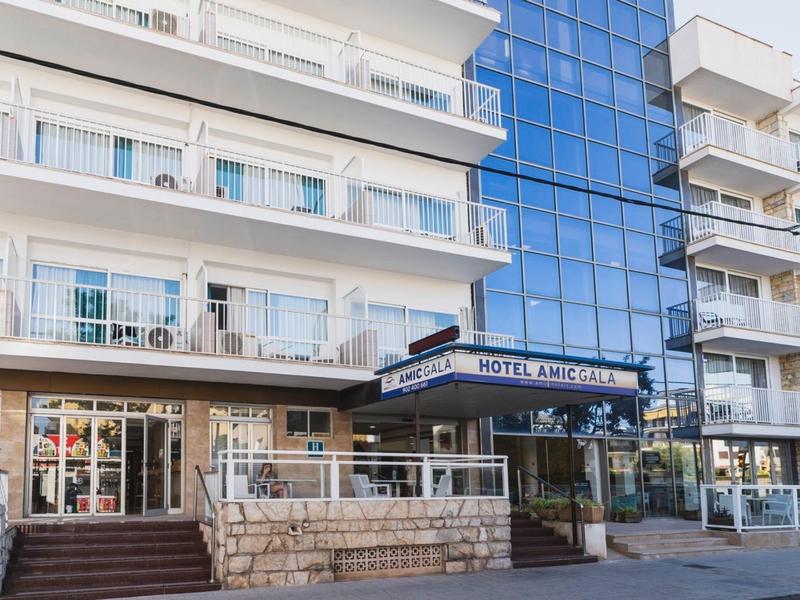 Multi-story hotel building with blue glass facade and entrance accessed by stairs.
