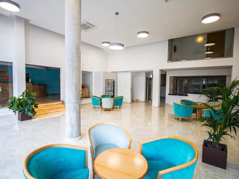 Modern, bright hotel lobby area with blue armchairs and round tables.