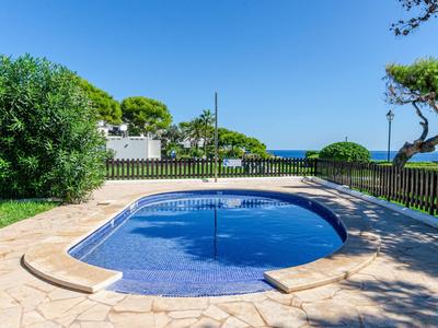 Kleiner Swimmingpool mit klarem Wasser in einem Garten mit Palmen und Blick auf das Meer.