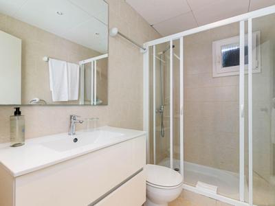 Helles Badezimmer mit Dusche, Waschtisch, Spiegel und Toilette in einem Hotelzimmer.