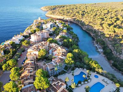 Luftaufnahme eines Resorts mit Pools, umgeben von Bäumen und nahe dem Meer.