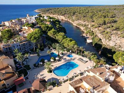 Luftaufnahme eines Hotels mit Pool an einer felsigen Küste und einem Fluss im Grünen.