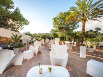 Freiluftterrasse mit weißen Möbeln, Palmen und Pflanzen für eine entspannte Urlaubsatmosphäre.