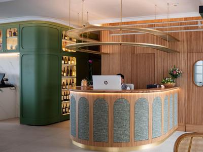 Modernes Hotelrezeptionsdesign mit geschwungenem Tresen, Holzvertäfelung und grünen Akzenten.