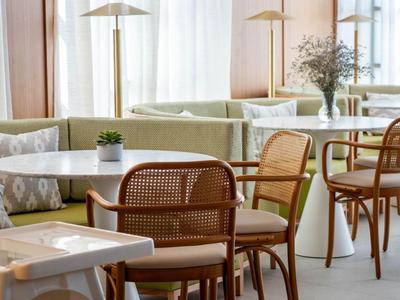 Modernes Hotelrestaurant mit hellem Interieur, Holzstühlen und Tischen sowie großen Fenstern.