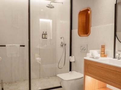 Modernes Badezimmer mit begehbarer Dusche, WC, Holzspiegel und Waschbecken in hellen Farben.