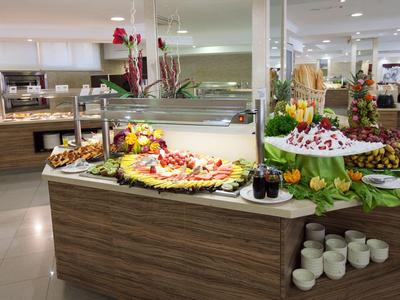 Buffet mit vielfältigen Obstplatten, Gebäck, Bechern und Dekoration in heller, moderner Umgebung.