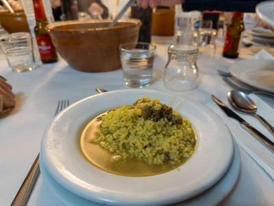 Ein Teller mit grüner Reisgericht in Soße auf einem gedeckten Esstisch.