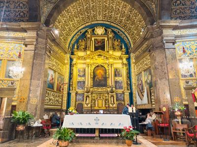 Prächtiger Altarraum einer Kirche mit vergoldeten Verzierungen, Gemälden und reich verzierten Säulen.