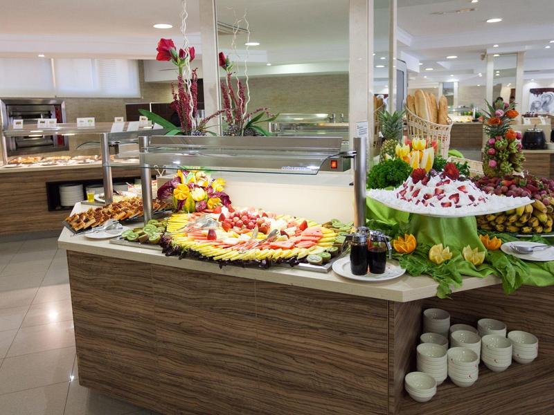 Buffet mit vielfältigen Obstplatten, Gebäck, Bechern und Dekoration in heller, moderner Umgebung.