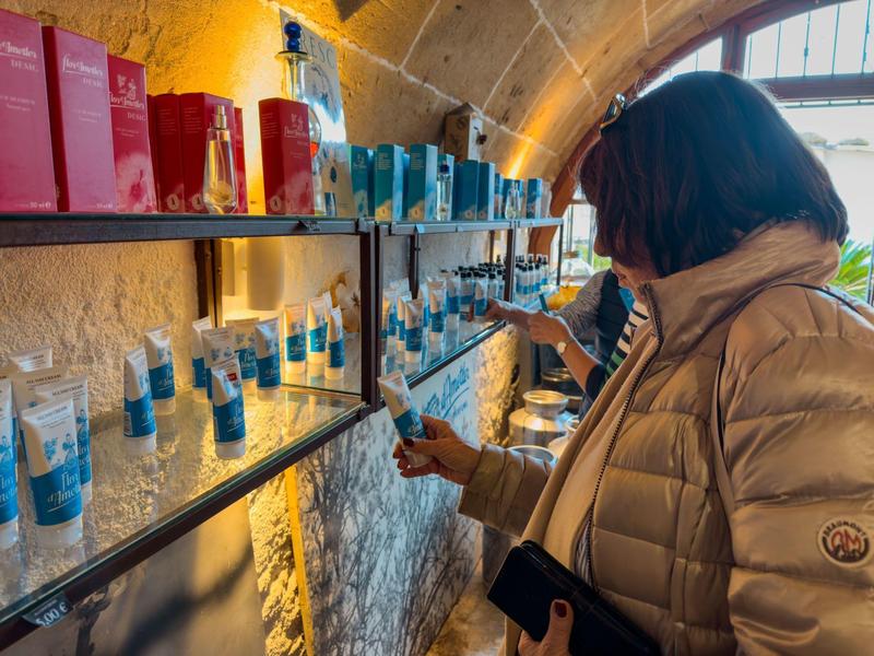 Zwei Frauen in warmen Jacken wählen in einem Laden mit Regalen aus farbigen Verpackungen und Gläsern.
