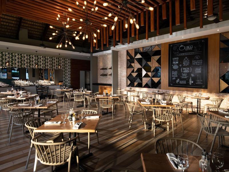 Modernes, lichtdurchflutetes Restaurant mit Holzdecke, Stühlen aus Rattan und dekorativen Wandtafeln.