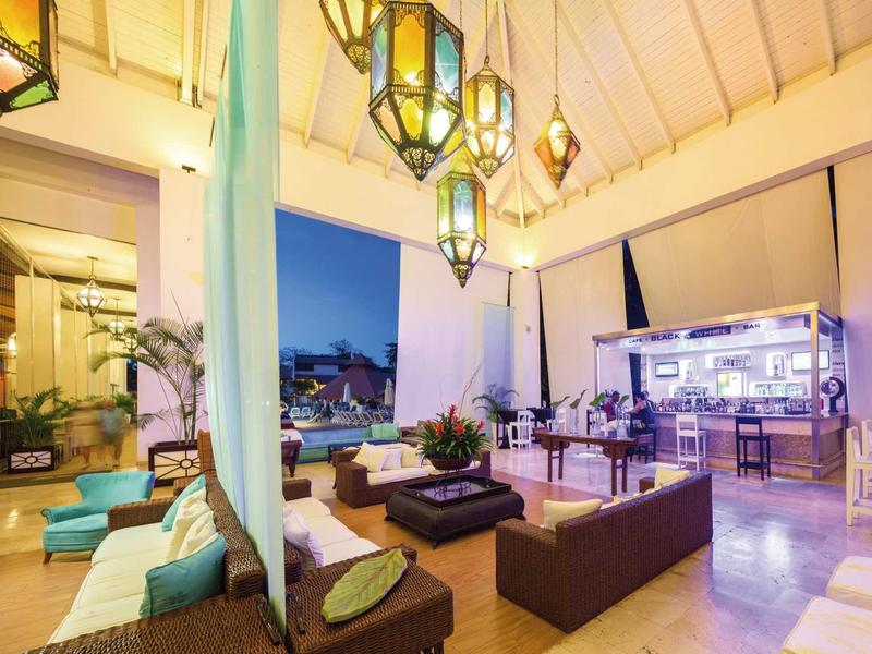 Moderne, helle Außenterrasse mit bequemen Sitzmöbeln, farbigen Kissen und leuchtenden Laternen.